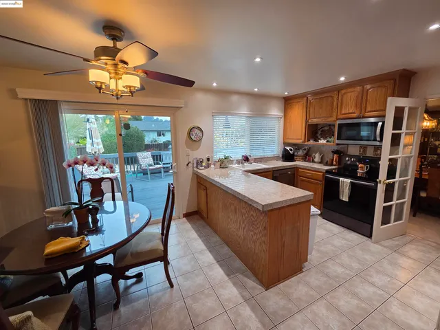 a kitchen with stainless steel appliances granite countertop a stove top oven a sink dishwasher a dining table and chairs with wooden floor