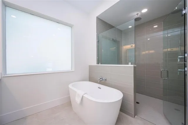 a view of a patio with couches table and chairs under an umbrella with large trees
