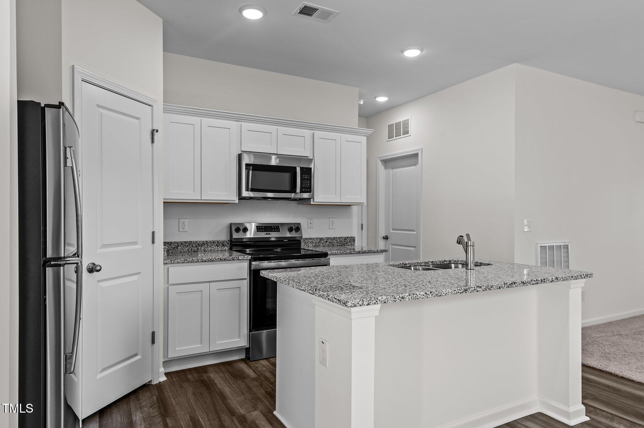 955 Embraer Way Spring Hope, NC 27882 - Photo 8 of 25 a kitchen with stainless steel appliances granite countertop a sink a stove a refrigerator a microwave and cabinets