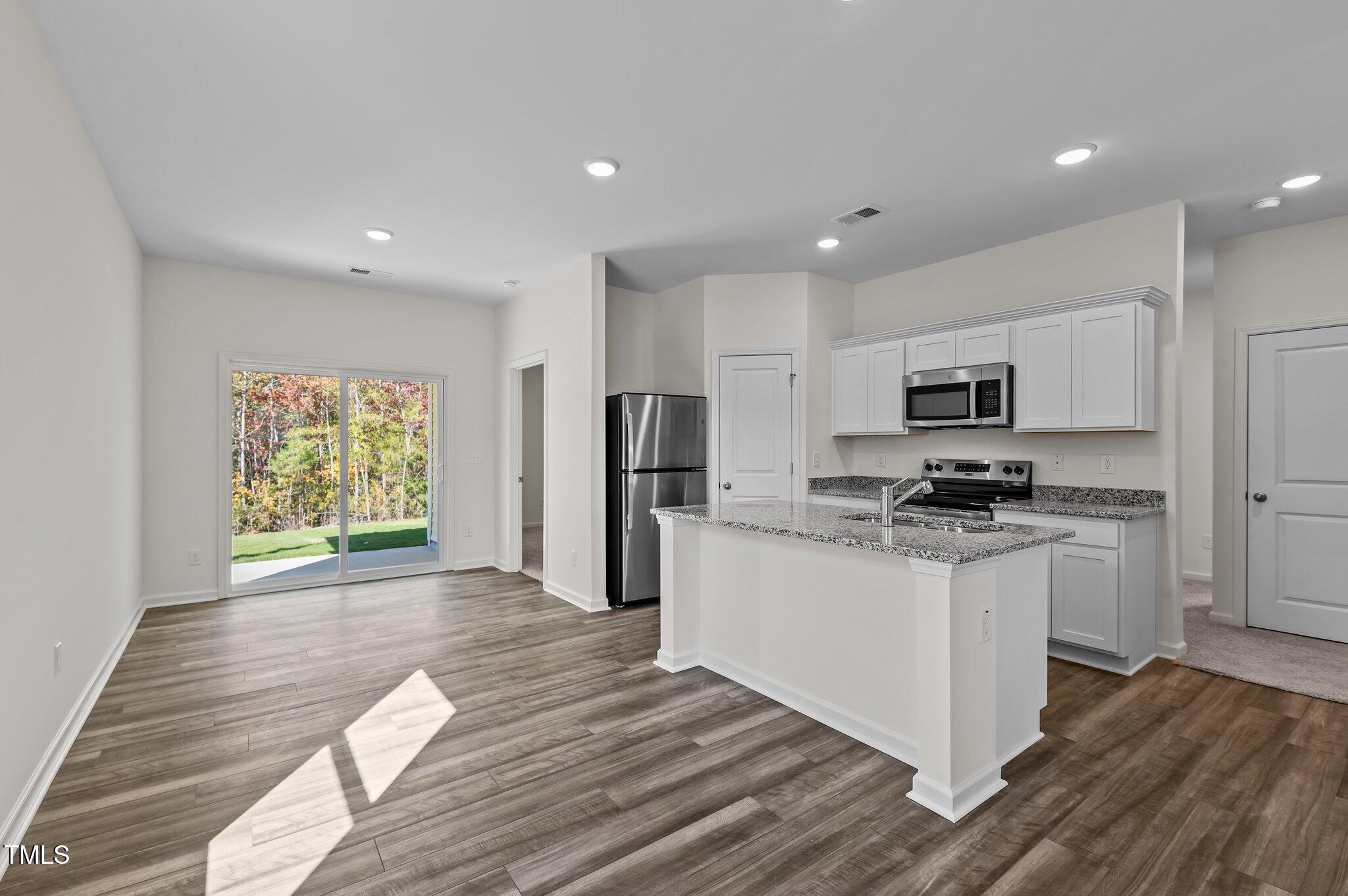 955 Embraer Way Spring Hope, NC 27882 - Photo 9 of 25 a kitchen with stainless steel appliances granite countertop a refrigerator oven a sink dishwasher and white cabinets with wooden floor