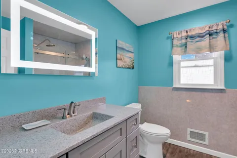 a bathroom with a granite countertop toilet sink and mirror