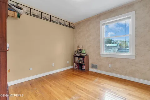 a view of a bedroom with wooden floor and windows