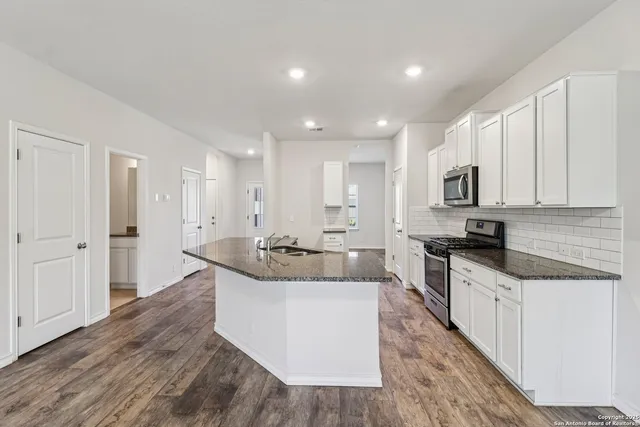 a large kitchen with stainless steel appliances granite countertop a lot of counter space and wooden floors