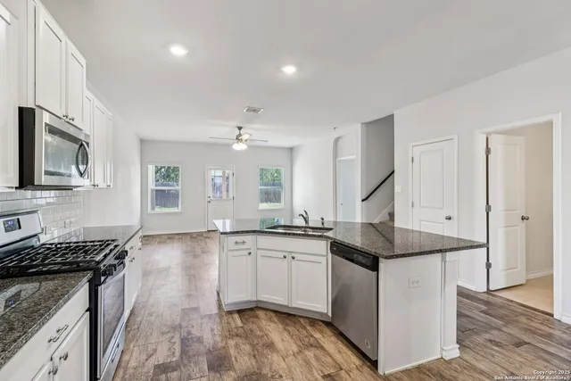 a kitchen with granite countertop a sink stove and cabinets