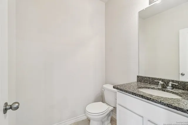 a bathroom with a granite countertop sink and a toilet