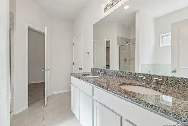 a bathroom with a granite countertop double sink and a mirror