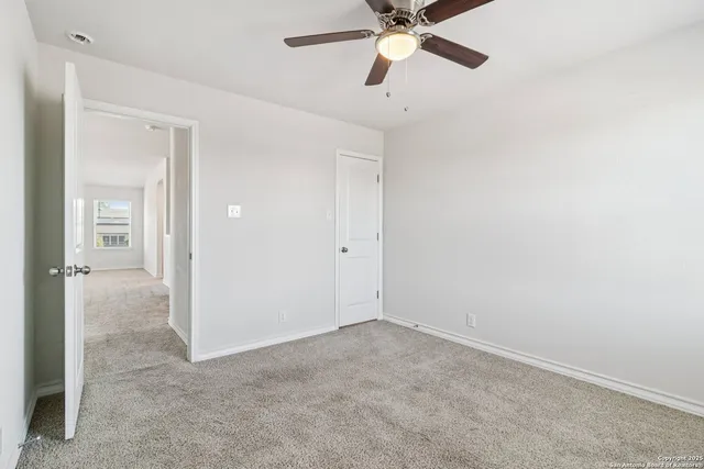 an empty room with closet and a chandelier fan