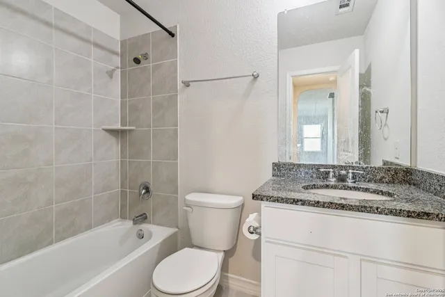 a bathroom with a granite countertop toilet sink and mirror