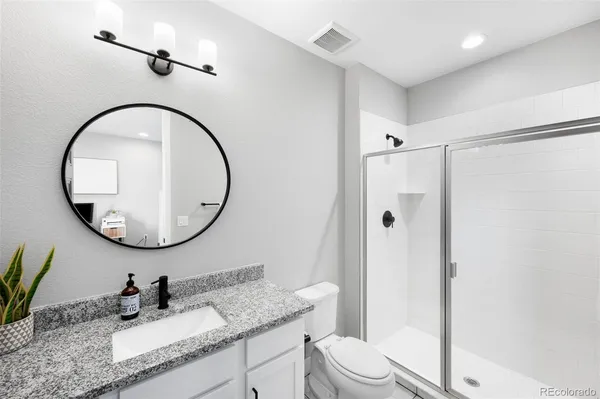 a bathroom with a granite countertop sink toilet mirror and shower