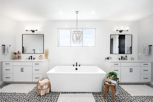 a spacious bathroom with a double vanity sink mirror and bathtub