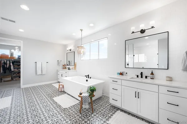 a spacious bathroom with a double vanity sink a mirror and a bathtub