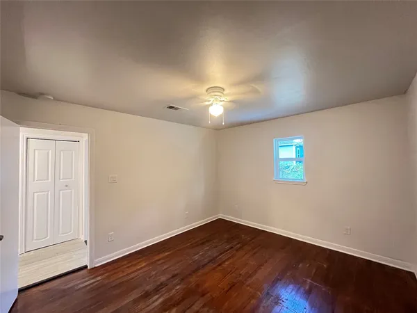 a view of an empty room with wooden floor and a window