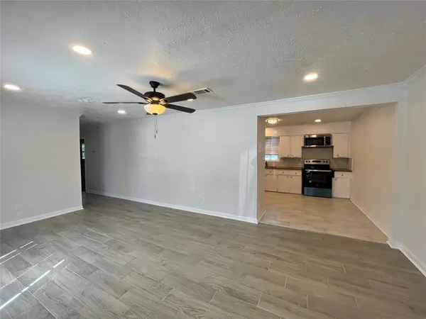 a view of an empty room with a ceiling fan and wooden floor