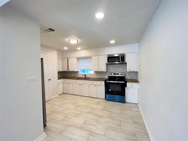 a kitchen with granite countertop white cabinets and stainless steel appliances