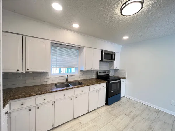 a kitchen with granite countertop a sink and cabinets