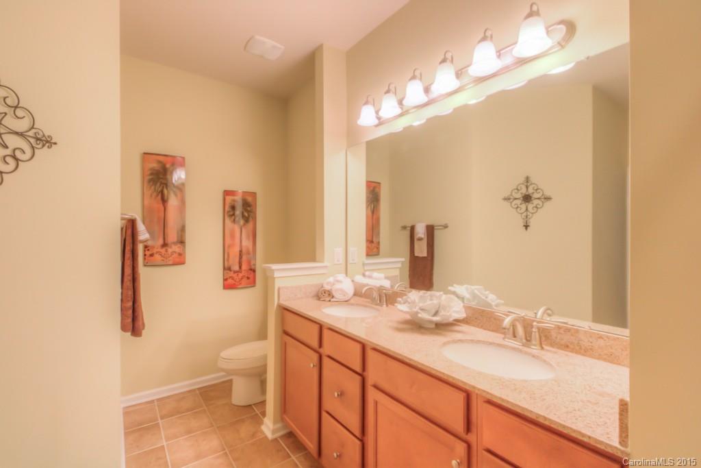 211 Chartwell Lane, Unit 211 Tega Cay, SC 29708 - Photo 11 of 19 a bathroom with a granite countertop sink a toilet and a mirror