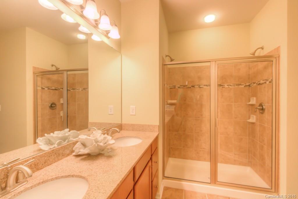 211 Chartwell Lane, Unit 211 Tega Cay, SC 29708 - Photo 12 of 19 a bathroom with a granite countertop sink a mirror and shower