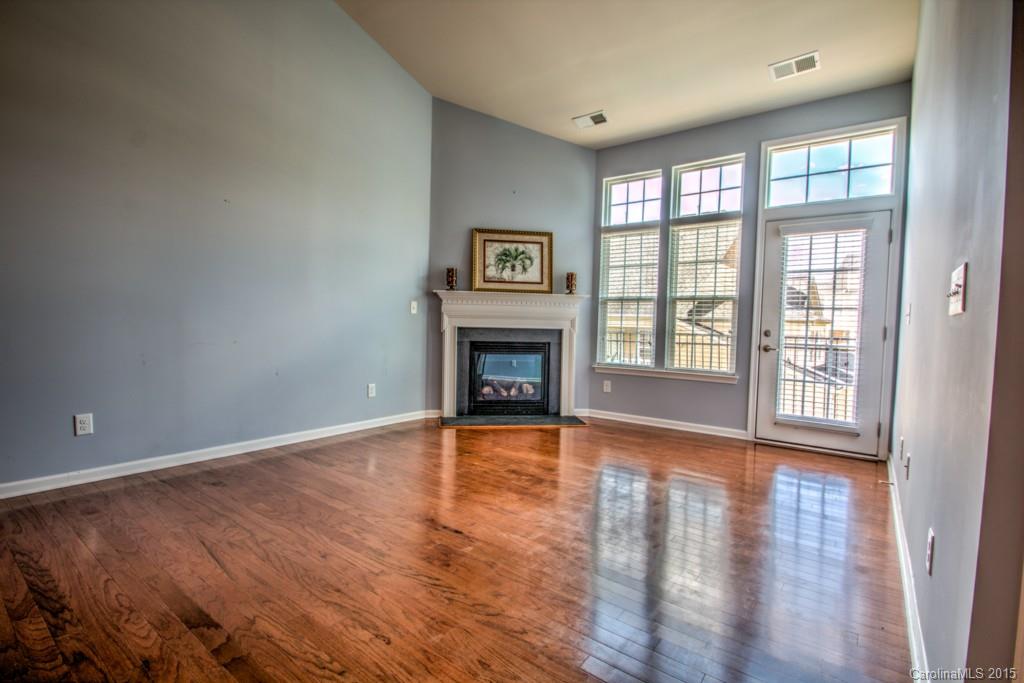 211 Chartwell Lane, Unit 211 Tega Cay, SC 29708 - Photo 7 of 19 an empty room with wooden floor fireplace and windows