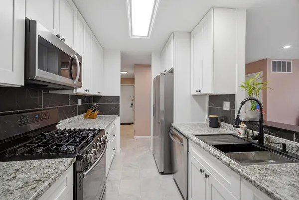a kitchen with stainless steel appliances granite countertop a sink stove and refrigerator