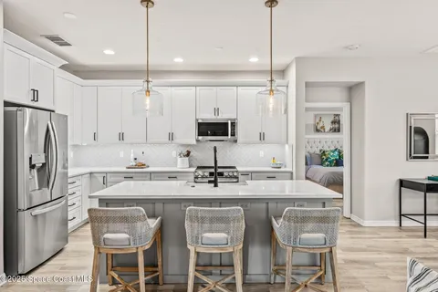 a kitchen with stainless steel appliances kitchen island granite countertop a refrigerator a stove and a sink with wooden floor