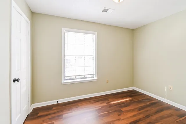 an empty room with wooden floor and windows