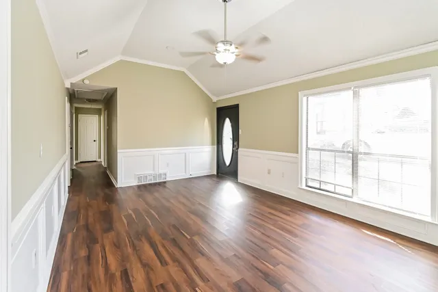 a view of an empty room with wooden floor and a window