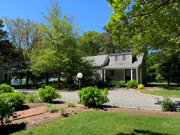 a front view of a house with a garden and trees