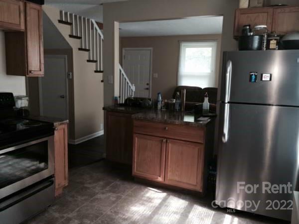 a kitchen with stainless steel appliances granite countertop a refrigerator a stove and a sink