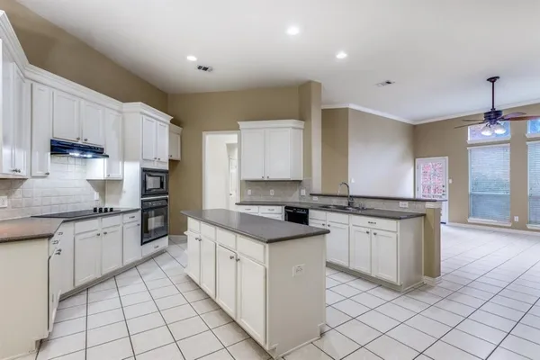 a kitchen with granite countertop white cabinets a sink dishwasher and a stove with wooden floor