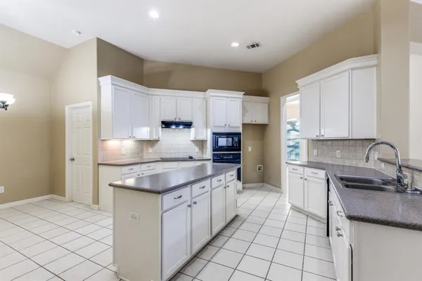 a kitchen with kitchen island granite countertop a sink stove and cabinets