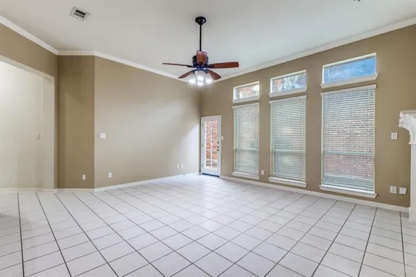 a view of an empty room with chandelier fan and window