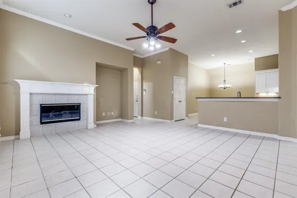a view of an empty room and kitchen with fireplace ceiling fan