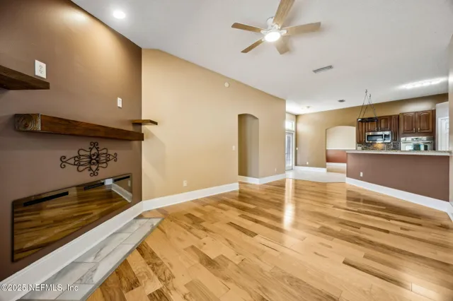 a view of an empty room with a window and wooden floor