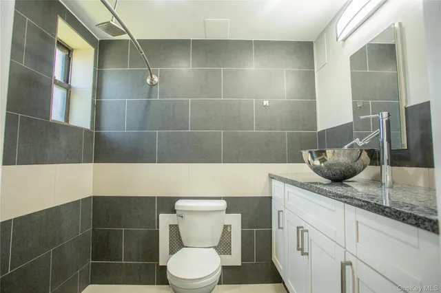 a bathroom with a granite countertop sink a toilet and mirror