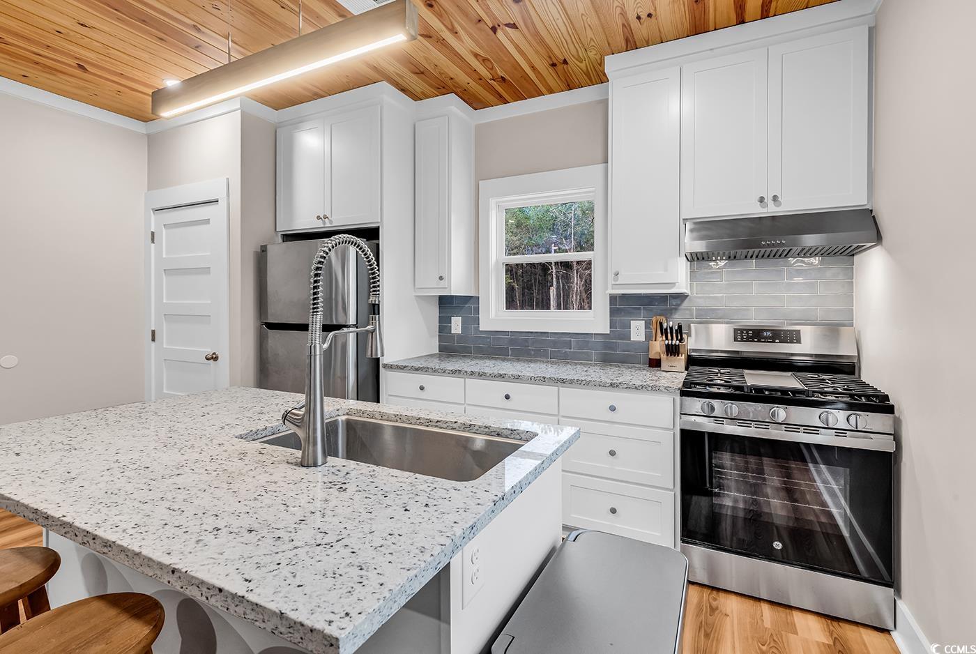 32 Old Place Kingstree, SC 29556 - Photo 13 of 40 Kitchen with appliances with stainless steel finishes, light stone countertops, wooden ceiling, a kitchen breakfast bar, and an island with sink