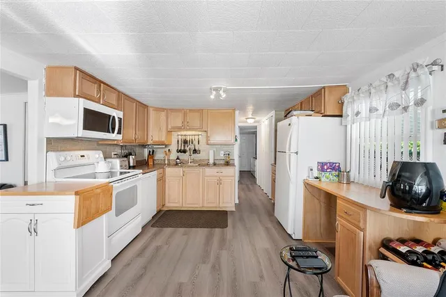 a kitchen with stainless steel appliances a stove top oven a sink a refrigerator white cabinets and wooden floor