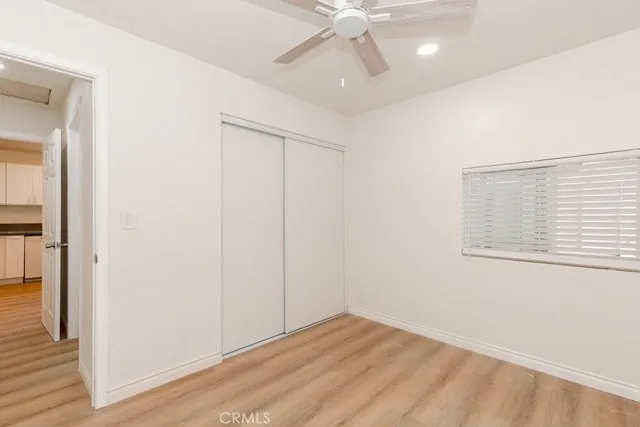 an empty room with wooden floor closet and windows