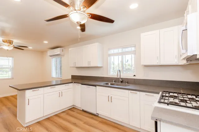 a kitchen with granite countertop white cabinets white appliances with a sink and dishwasher