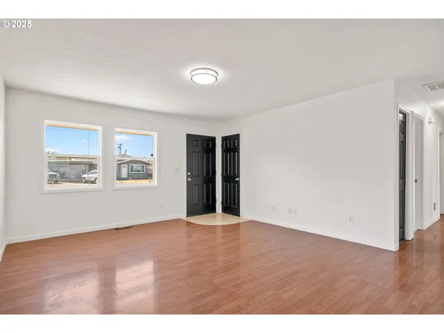 an empty room with wooden floor and windows