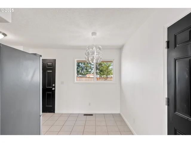 a view of a refrigerator in kitchen and an empty room