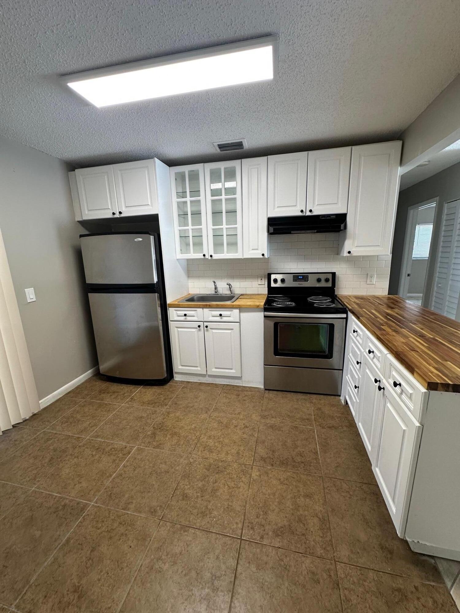 4810 Davis Road, Unit 4818 Lake Worth, FL 33461 - Photo 5 of 12 a kitchen with granite countertop a refrigerator stove and sink