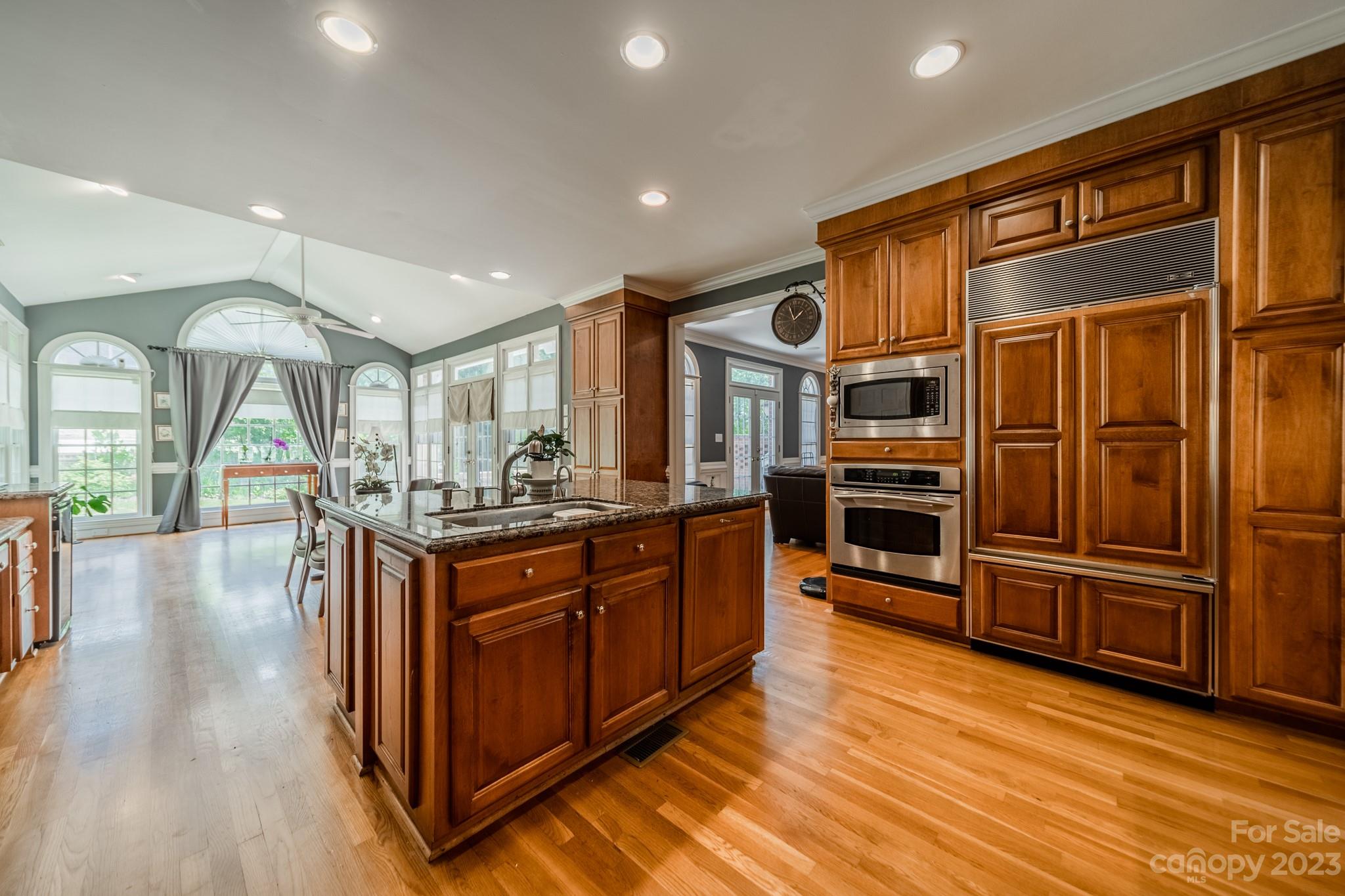1439 Windy Ridge Road Charlotte, NC 28270 - Photo 13 of 46 a kitchen with stainless steel appliances granite countertop a refrigerator a sink dishwasher a stove and a dining table with wooden floor