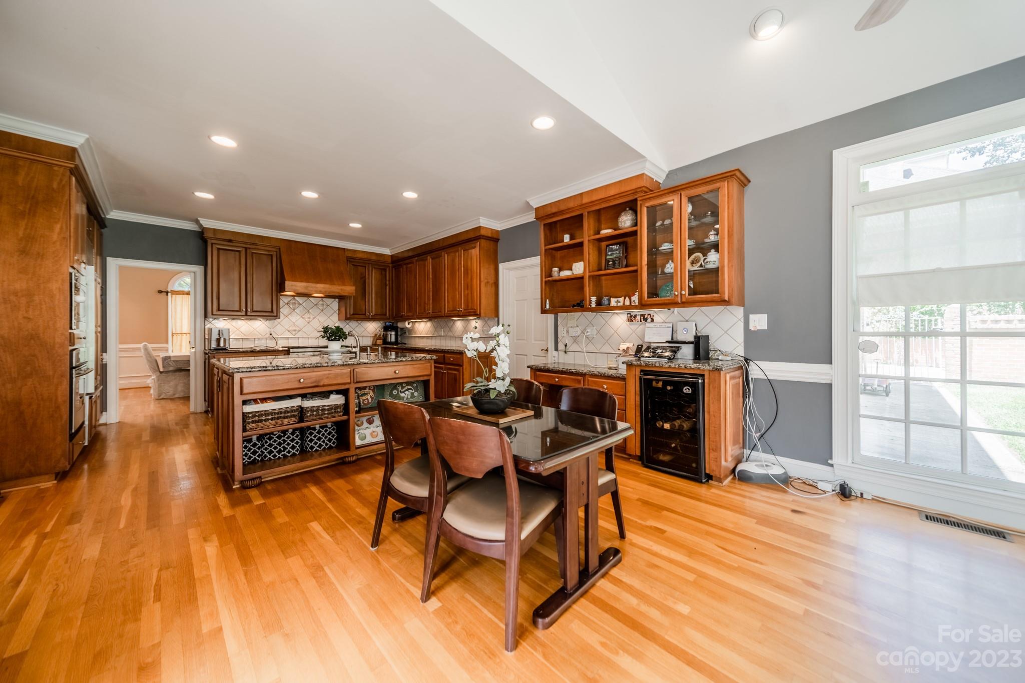 1439 Windy Ridge Road Charlotte, NC 28270 - Photo 16 of 46 a kitchen with stainless steel appliances kitchen island granite countertop a stove a refrigerator a sink a dining table and chairs with wooden floor