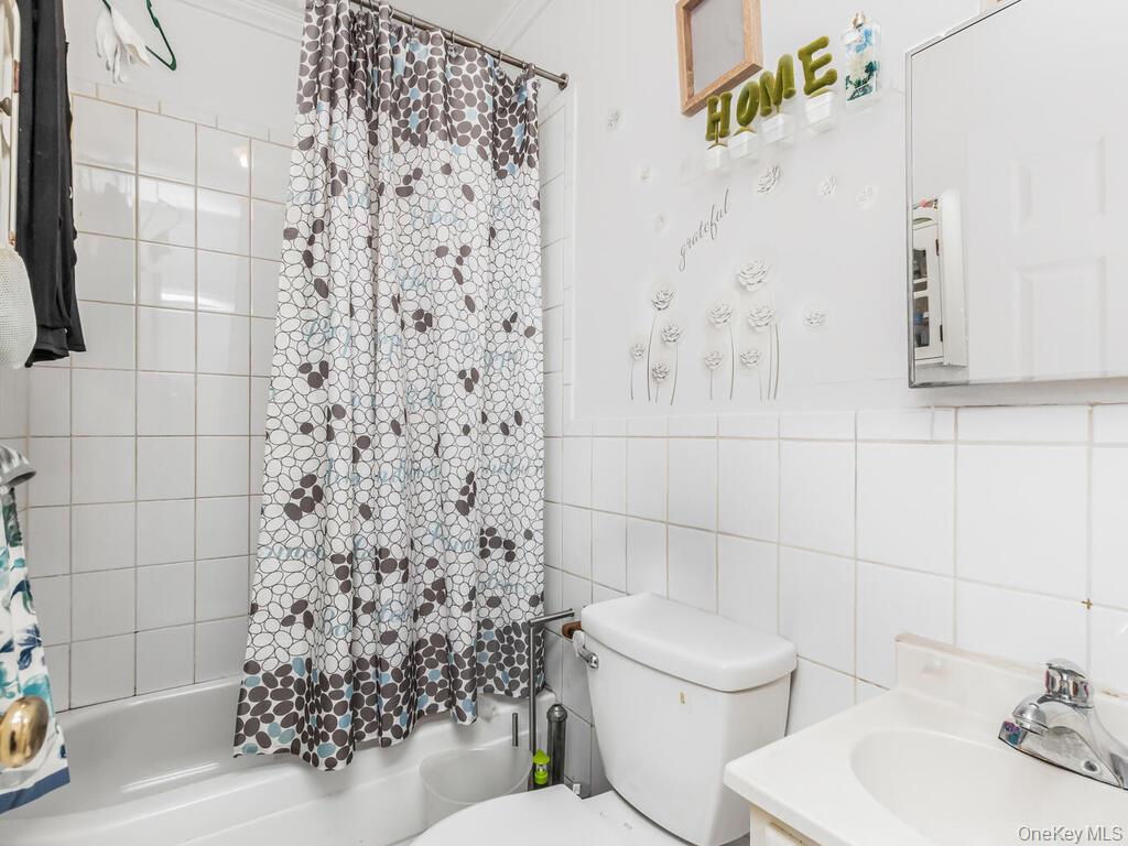 2108 Arthur Avenue Bronx, NY 10457 - Photo 5 of 12 a bathroom with a toilet and a shower curtain