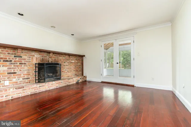 an empty room with wooden floor and fireplace