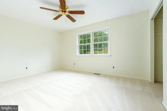 an empty room with windows and fan