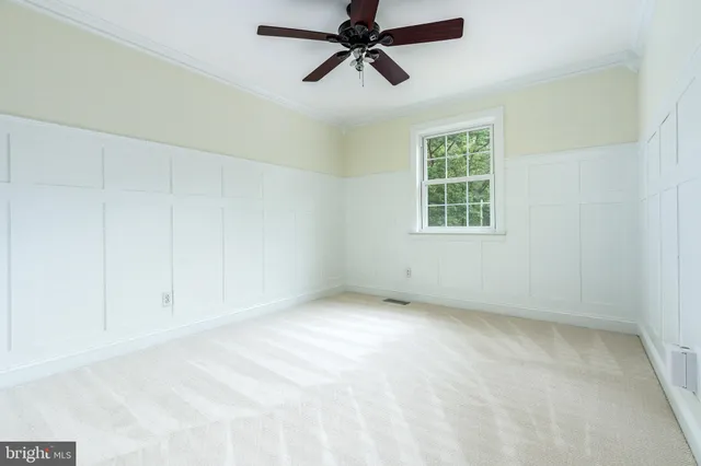 an empty room with chandelier fan and windows