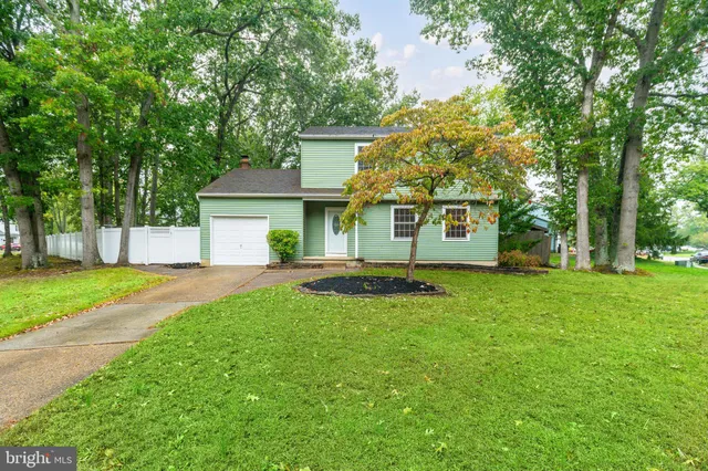 a front view of a house with a yard and trees