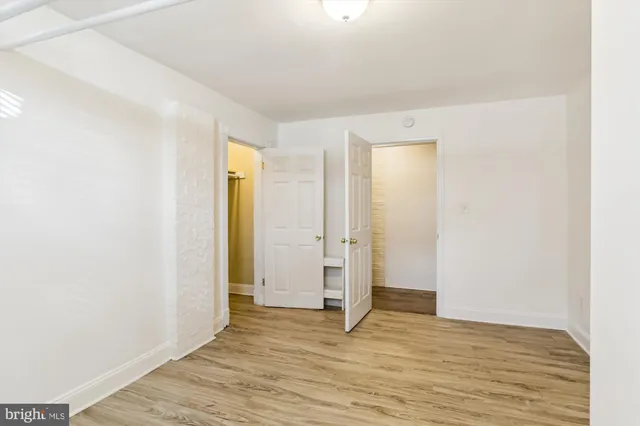 a view of an empty room with wooden floor and closet