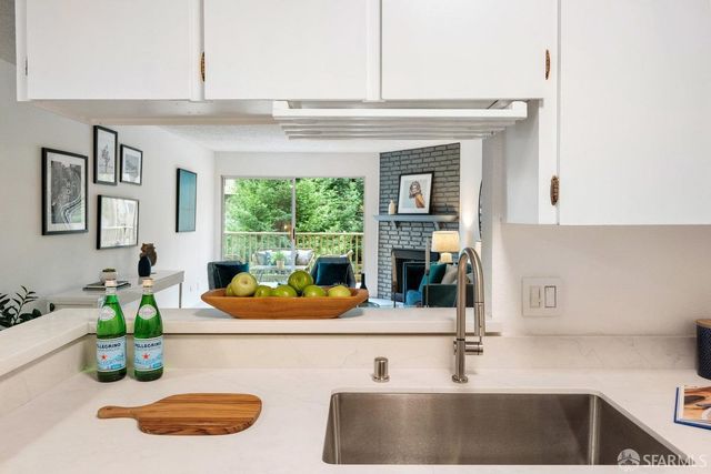 view of kitchen with stainless steel appliances granite countertop a sink and a white cabinets